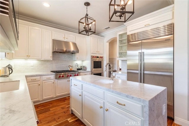 34072 Lily Rd, Yucaipa, CA 92399 - kitchen featuring appliances with stainless steel finishes, under cabinet range hood, a sink, arched walkways, and white cabinets