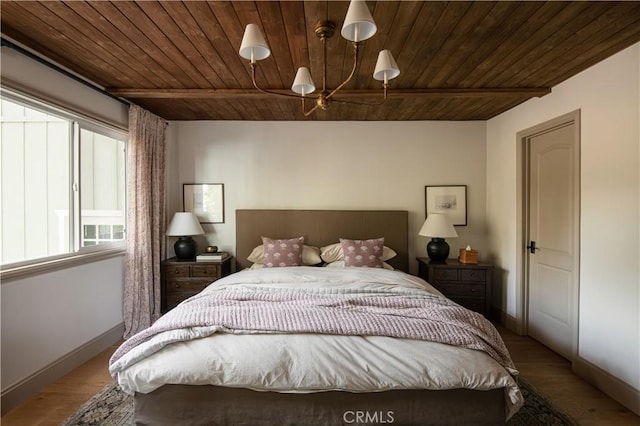 bedroom featuring wooden ceiling, baseboards, wood finished floors, and a chandelier