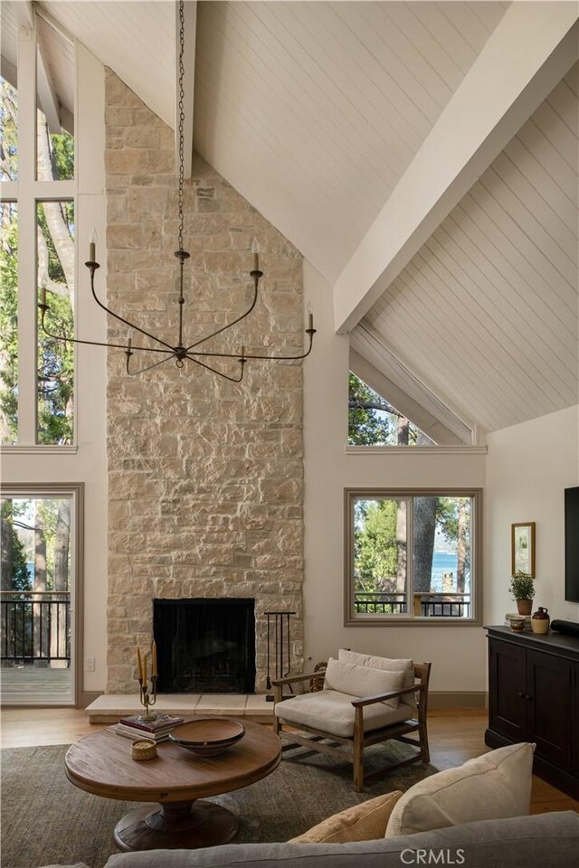living area featuring a fireplace, high vaulted ceiling, beamed ceiling, and light wood finished floors