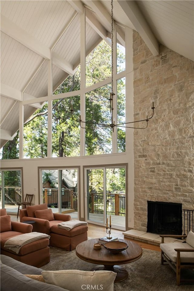 living area featuring a fireplace, wood finished floors, high vaulted ceiling, and beamed ceiling