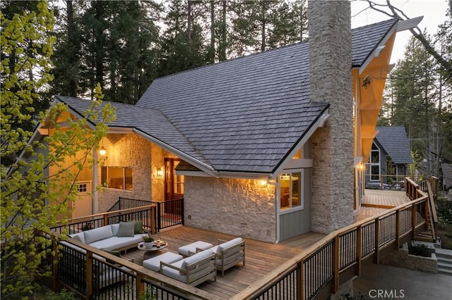back of house featuring an outdoor hangout area, a chimney, a deck, and stone siding