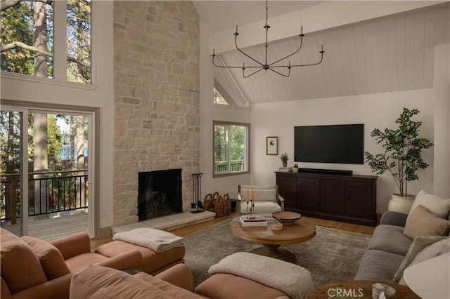 living room featuring high vaulted ceiling, a notable chandelier, wood finished floors, and a fireplace