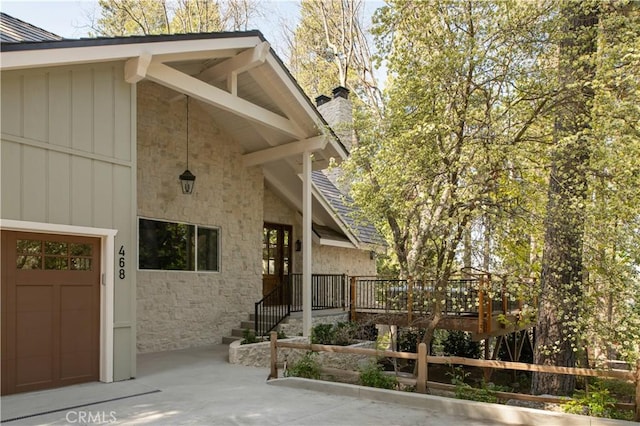 doorway to property featuring a chimney, a deck, and stone siding