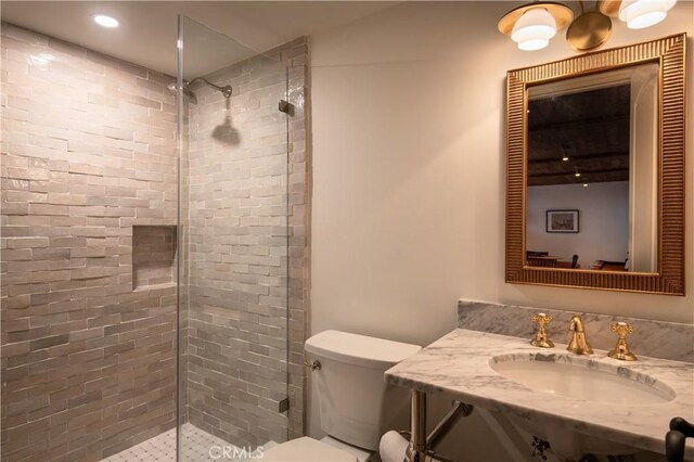 bathroom featuring recessed lighting, vanity, a tile shower, and toilet