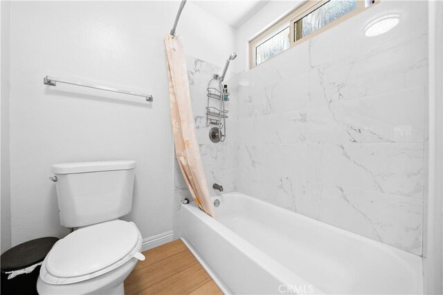 full bathroom featuring baseboards, wood finished floors, shower / bath combo, and toilet
