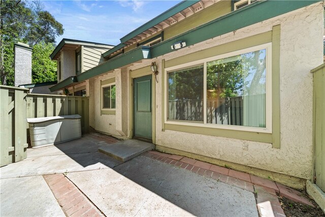 doorway to property featuring fence, stucco siding, and a patio area