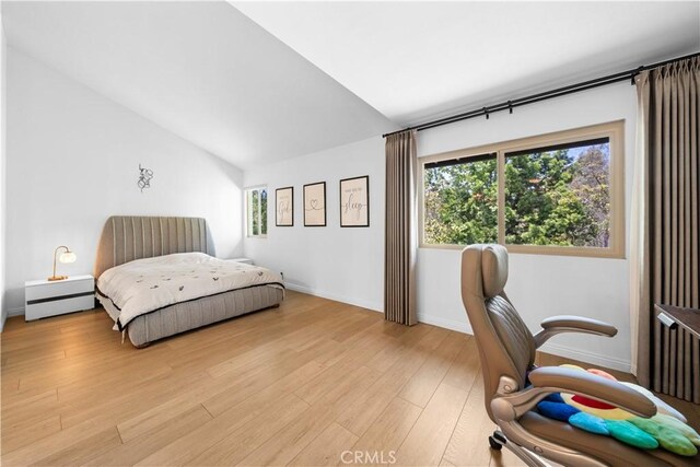 bedroom featuring baseboards, vaulted ceiling, and light wood-style flooring