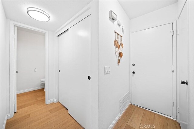 hallway with baseboards, light wood-type flooring, and visible vents