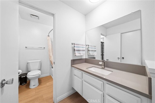 bathroom with visible vents, shower / tub combo with curtain, vanity, wood finished floors, and toilet
