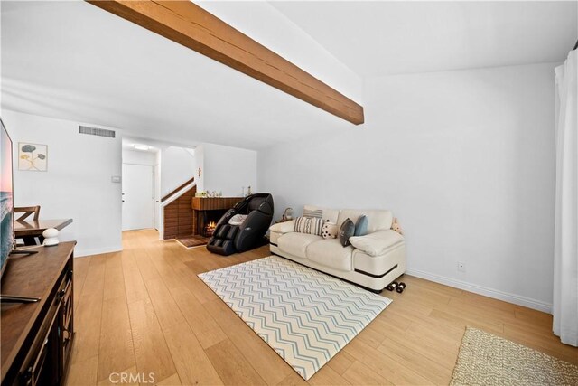 living area featuring visible vents, stairs, wood finished floors, and beamed ceiling