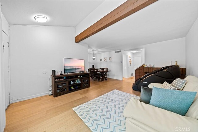 living area featuring visible vents, beam ceiling, and wood finished floors