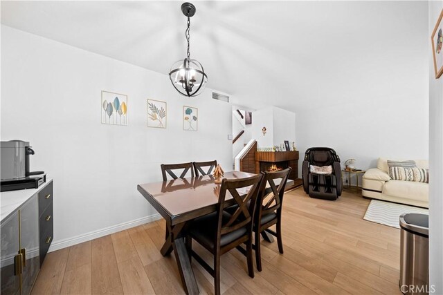 dining space featuring baseboards, visible vents, an inviting chandelier, and light wood finished floors