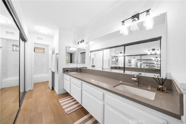 bathroom with double vanity, a sink, wood finished floors, and visible vents