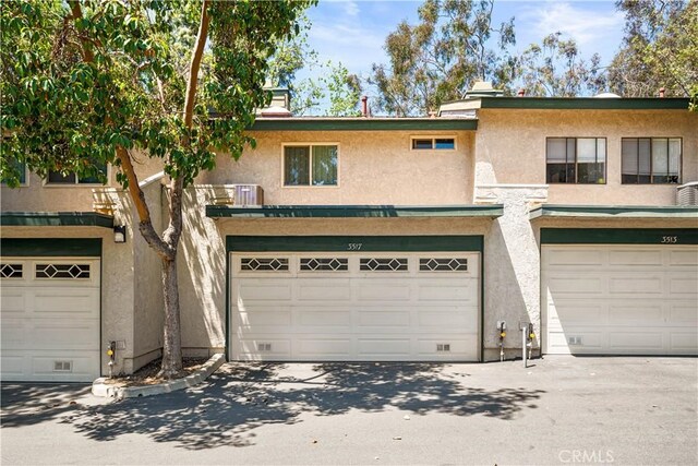 townhome / multi-family property featuring central AC, an attached garage, and stucco siding