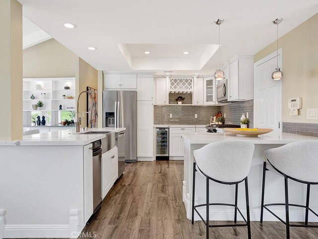 31062 Flying Cloud Dr, Laguna Niguel, CA 92677 - kitchen featuring open shelves, appliances with stainless steel finishes, beverage cooler, wood finished floors, and a kitchen bar