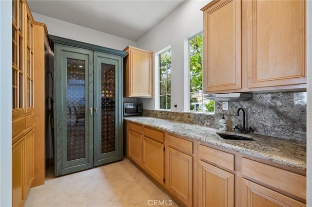 2438 Vista Del Sol Ln, Verne, CA 91750 - kitchen featuring light stone counters, a sink, stainless steel microwave, light tile patterned floors, and backsplash