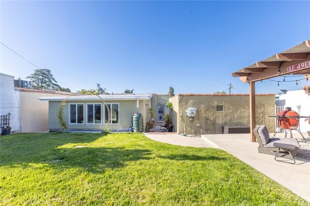 back of property with a lawn, a patio area, and stucco siding