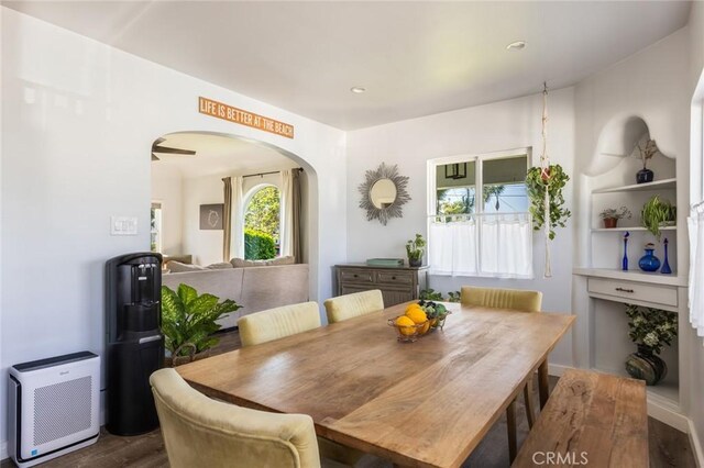 dining space featuring arched walkways, recessed lighting, and wood finished floors