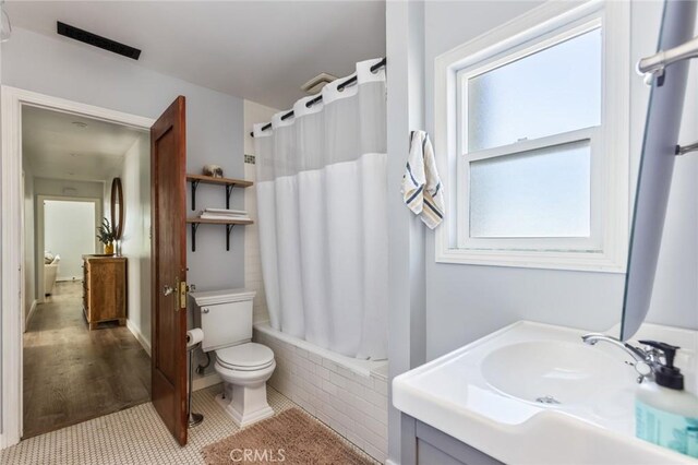 full bath featuring visible vents, shower / tub combo with curtain, vanity, wood finished floors, and toilet