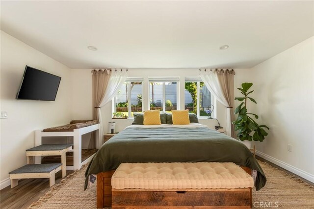 bedroom featuring baseboards, wood finished floors, and multiple windows