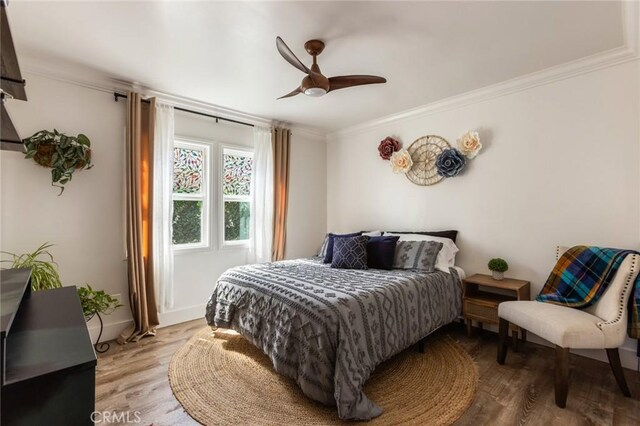 bedroom featuring ceiling fan, ornamental molding, and wood finished floors