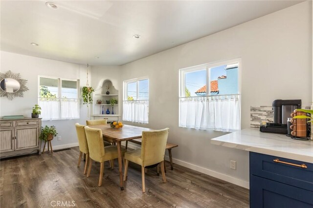 dining area featuring baseboards, a healthy amount of sunlight, and dark wood-type flooring