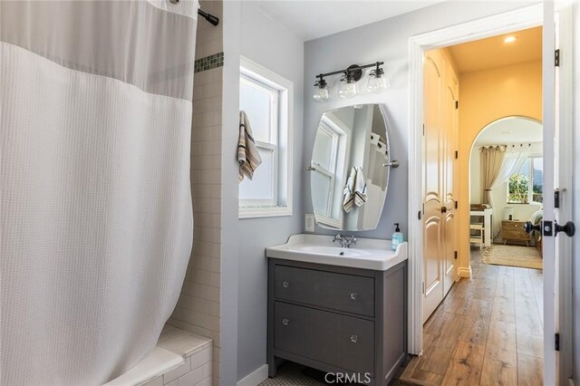 full bath with vanity, baseboards, a shower with shower curtain, and hardwood / wood-style floors