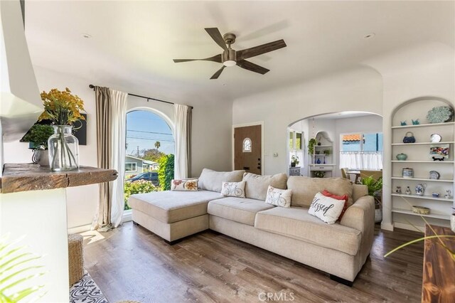 living area with a healthy amount of sunlight, arched walkways, ceiling fan, and wood finished floors