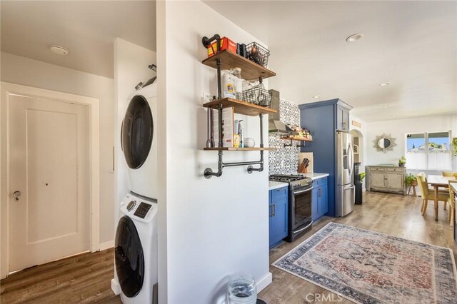 washroom with laundry area, recessed lighting, stacked washing maching and dryer, and wood finished floors