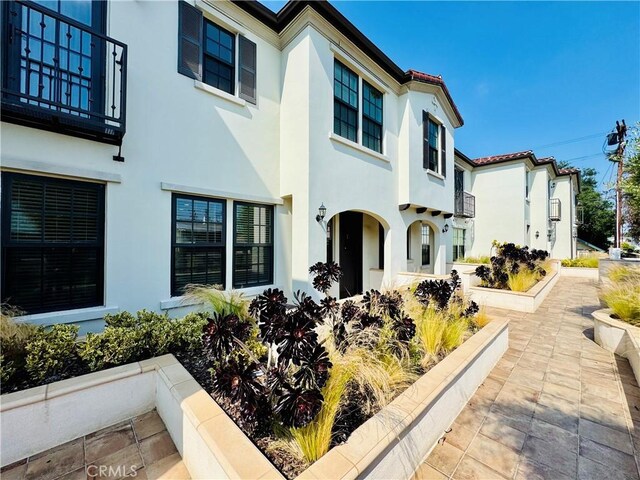 view of front facade featuring stucco siding and a balcony