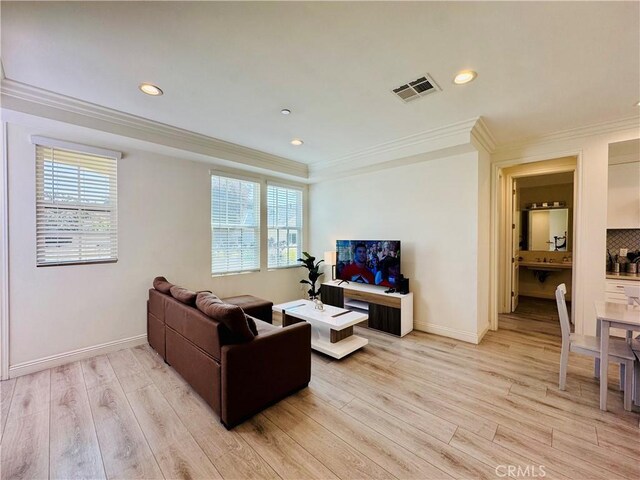 living room featuring plenty of natural light, ornamental molding, and light wood-type flooring