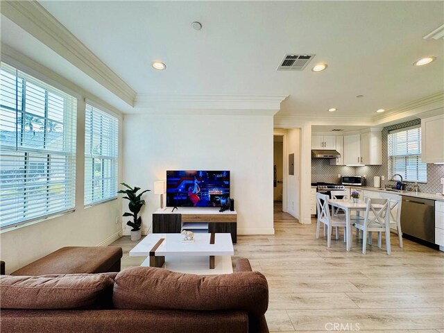 living area with visible vents, baseboards, light wood-style floors, ornamental molding, and recessed lighting