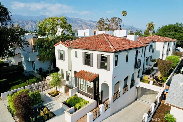 back of property featuring fence, a mountain view, stucco siding, and a tiled roof