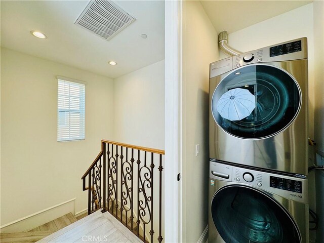 laundry room featuring laundry area, stacked washing maching and dryer, recessed lighting, baseboards, and visible vents