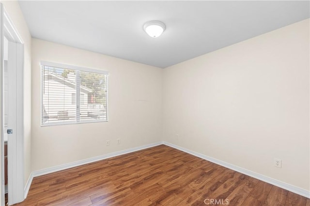 empty room with baseboards and wood finished floors