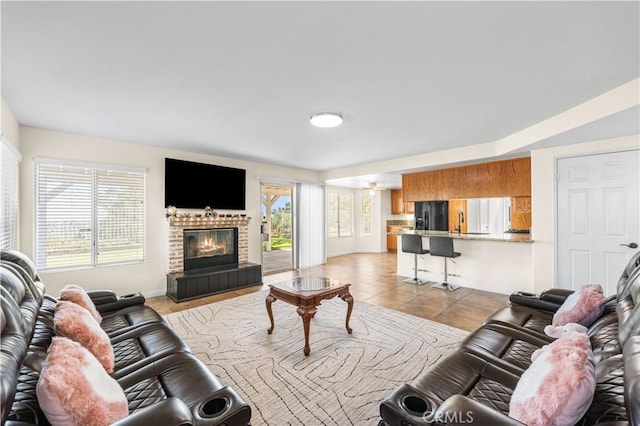 living room featuring baseboards, light tile patterned floors, and a tile fireplace