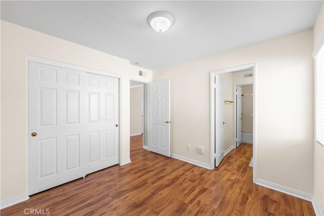 unfurnished bedroom featuring baseboards, visible vents, wood finished floors, and a closet