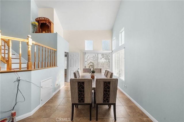 tiled dining area featuring stairs, baseboards, and a towering ceiling