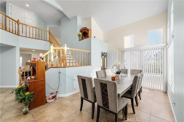 dining area with a high ceiling, baseboards, and stairway