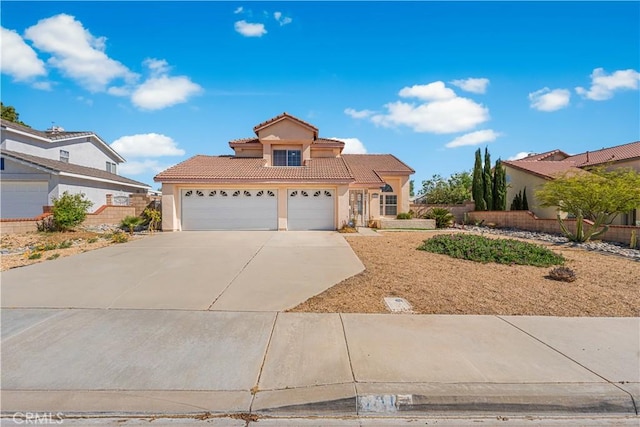 view of front of property featuring fence, stucco siding, a tiled roof, concrete driveway, and an attached garage