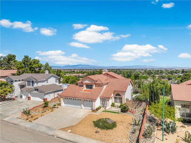view of front of house featuring a garage, fence, a tiled roof, a mountain view, and driveway