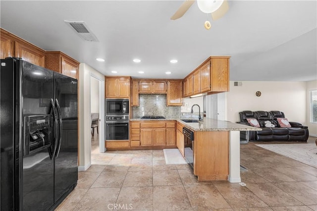 kitchen with visible vents, light stone countertops, a sink, black appliances, and open floor plan