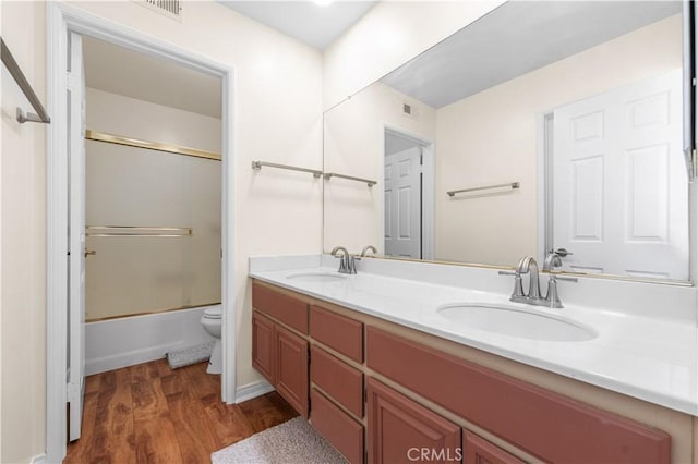 bathroom featuring double vanity, a sink, wood finished floors, and toilet
