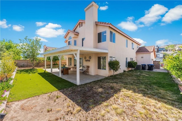 rear view of house featuring a tile roof, a lawn, a patio area, a fenced backyard, and stucco siding