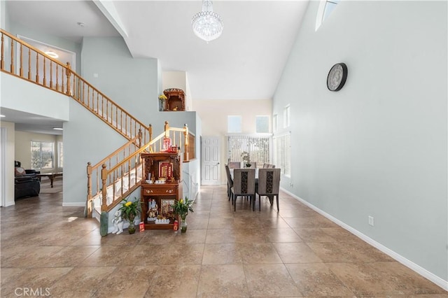 interior space featuring baseboards, stairs, a chandelier, and a towering ceiling