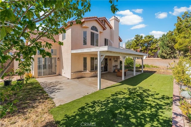 back of house featuring fence, stucco siding, a chimney, a lawn, and a patio