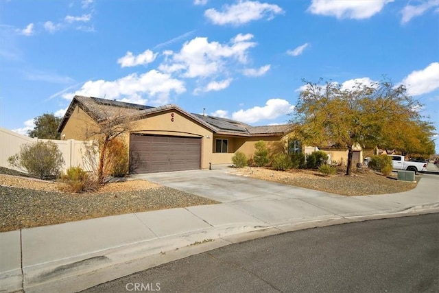 905 Broadway Ave, Barstow, CA 92311 - ranch-style house with driveway, fence, roof mounted solar panels, an attached garage, and stucco siding