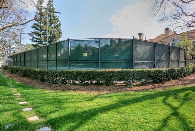 view of sport court with a lawn and fence
