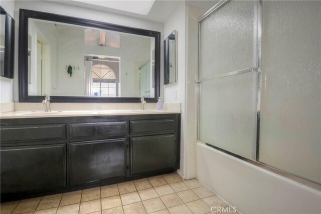 full bathroom featuring double vanity, tile patterned floors, a sink, and bath / shower combo with glass door