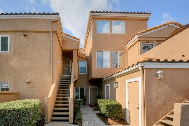 exterior space with a tiled roof, stairs, and stucco siding